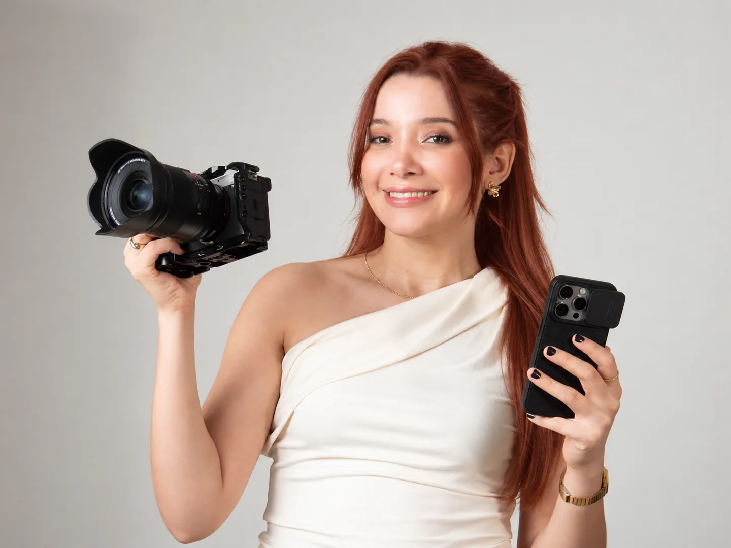 Amanda Tallya segurando uma câmera e um celular