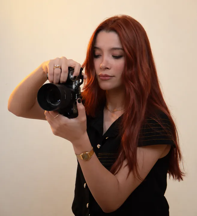 Amanda Tallya fotografando com uma câmera